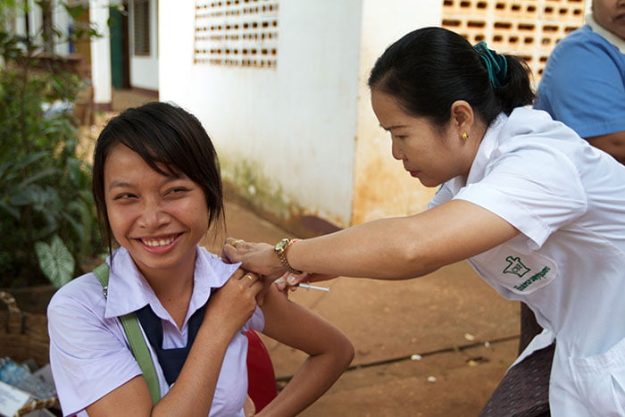 Young person receiving a vaccine from a community health worker.
